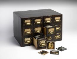 wooden chest of drawers with glass lantern slides
