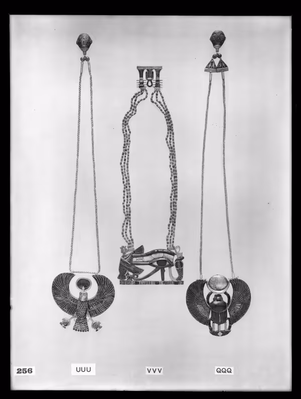Image of negative of three necklaces: the left one with a falcon, the middle one with a vulture, eye and cobra, and the right one with a winged scarab