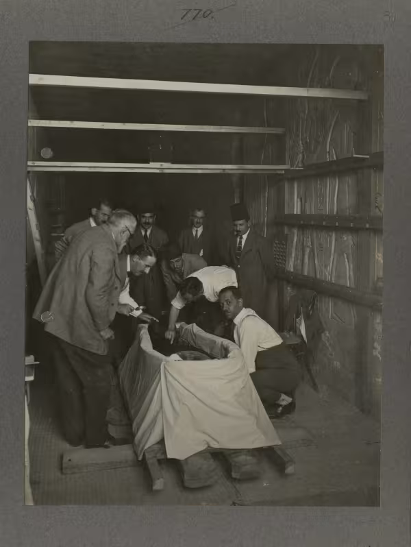 image of Carter and excavation team around coffin during the unwrapping, from Burton's album