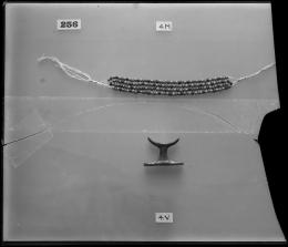 Image of negative of beaded jewellery and small amulet