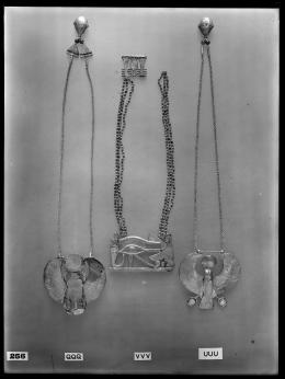 Image of negative of the back of three necklaces: the left one with a winged scarab, the middle one with a vulture, eye and cobra, and the right one with a falcon